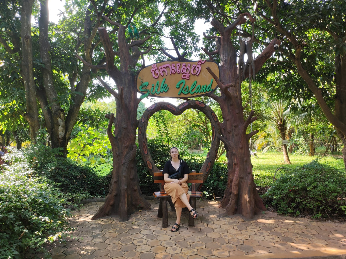 Sitting beneath Silk Island Community Center entrance sign surrounded by trees and garden scenery